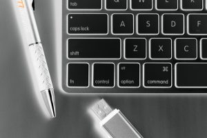Running a Marketing Company. Pen, keyboard, and flash drive image in inverted black and white color.