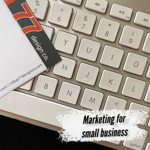 Image of 77 Design Co notepad sitting on computer keyboard with white splattered background that says Marketing for small business.
