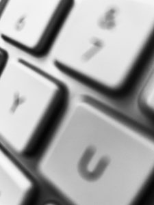 Is Your Company Blogging? Why Not? A black and white unfocused image of a computer keyboard.